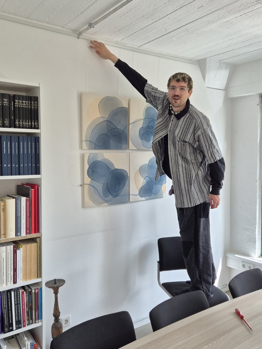 Ein Mann auf einer Leiter hängt Bilder auf