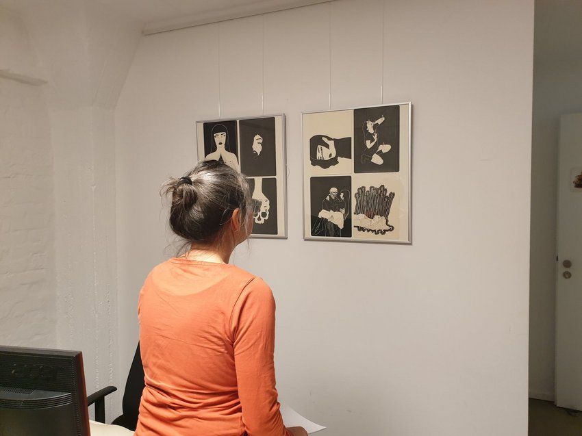 Eine Frau vor ausgestellten Zeichnungen